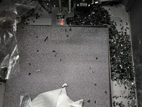 Freight damage example: shattered glass scattered across the build plate inside a printer